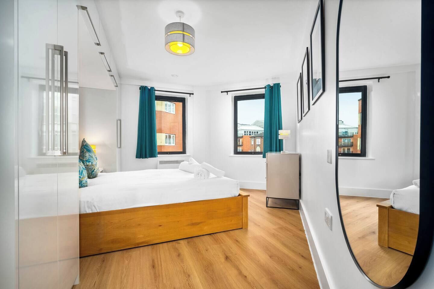 Una camera d'albergo moderna con un letto grande, un comodino, uno specchio e vista sulla città.