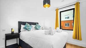 A modern bedroom with a bed, pillows, a nightstand, a lamp, and a window with curtains. - #116 Modern 2 bed - 10 mins from Bullring & Grand Central (West Midlands)