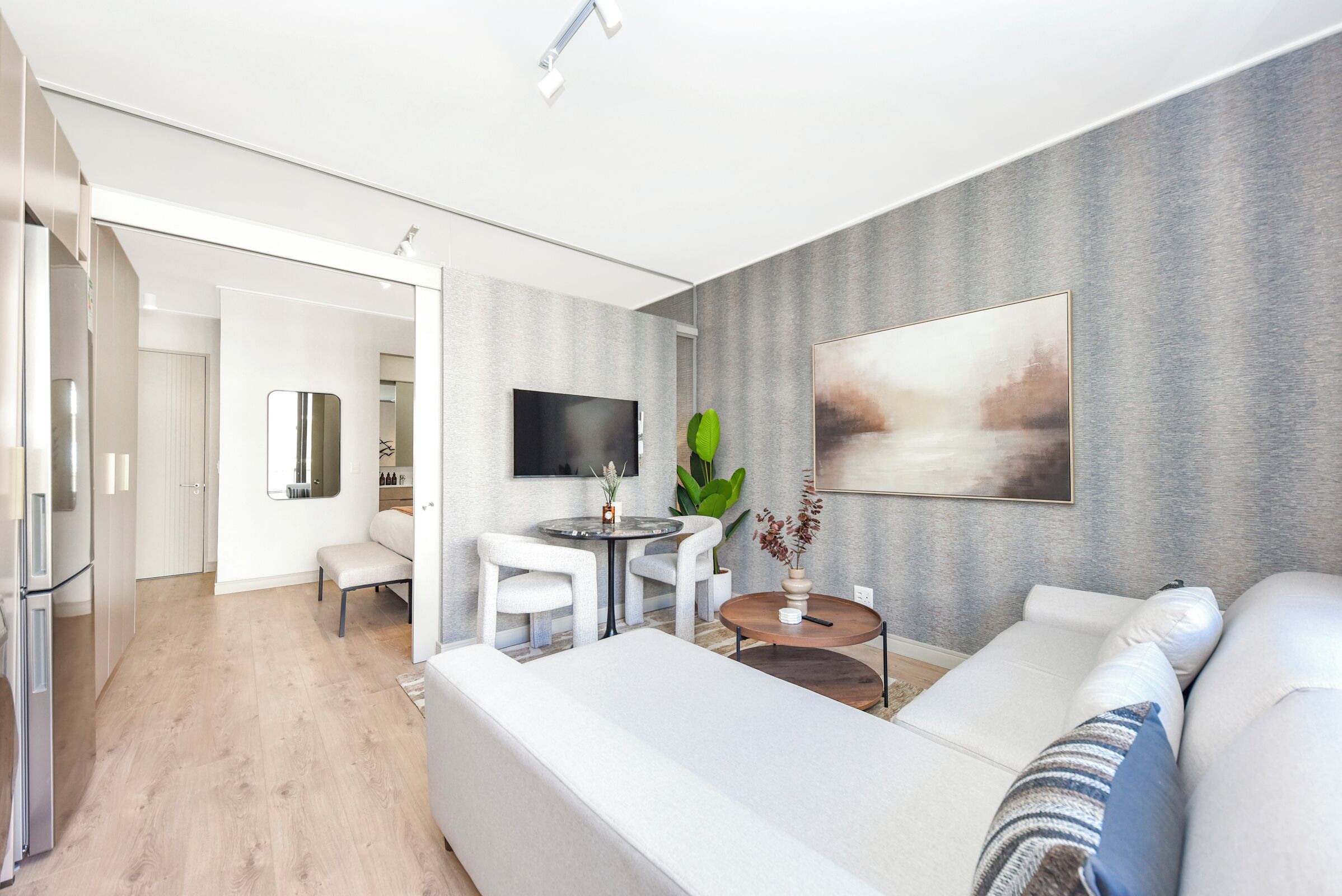 A modern living room with a sofa, a coffee table, and a TV mounted on the wall.