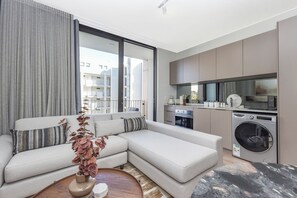 A modern apartment with a large living area, a kitchen with appliances, and a view of the city. - One Rosebank | Premium City Escape and Location (Johannesburg)