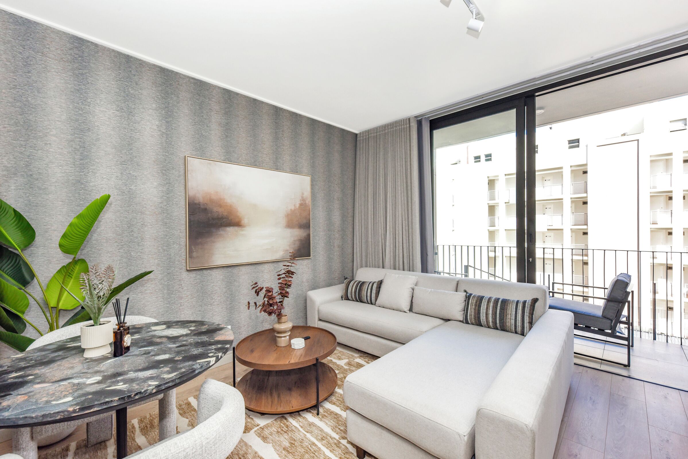 Een moderne woonkamer met een bank, een ronde salontafel en een schilderij aan de muur.