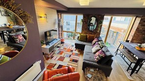 Ein modernes Wohnzimmer mit einer Couch, einem Esstisch und einem großen Fenster.