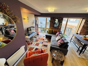 Ein modernes Wohnzimmer mit einer Couch, einem Esstisch und einem großen Fenster.