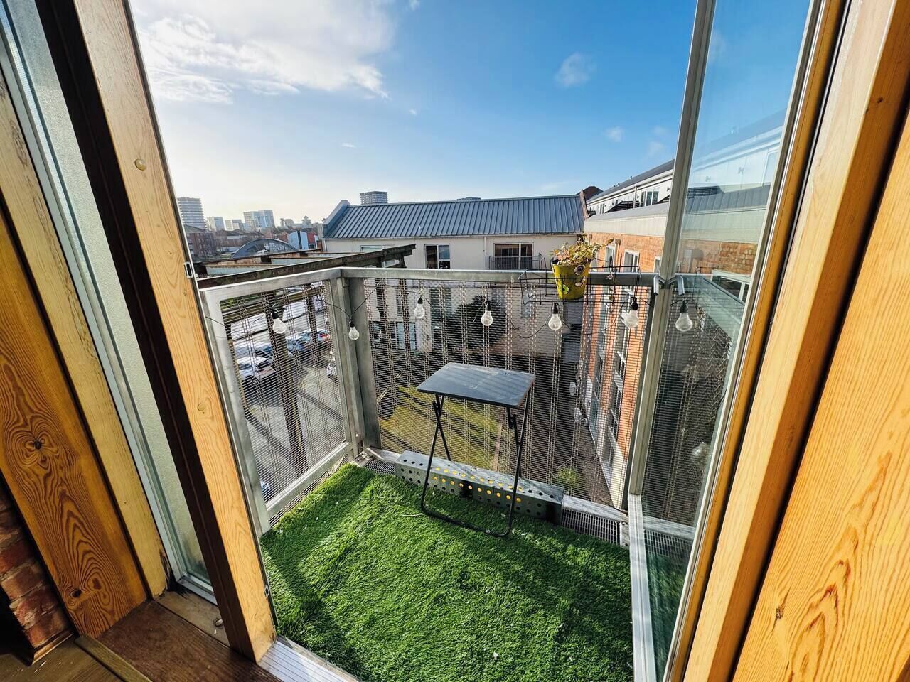 Een balkon met een tafeltje, een stoel en een plant in een pot.