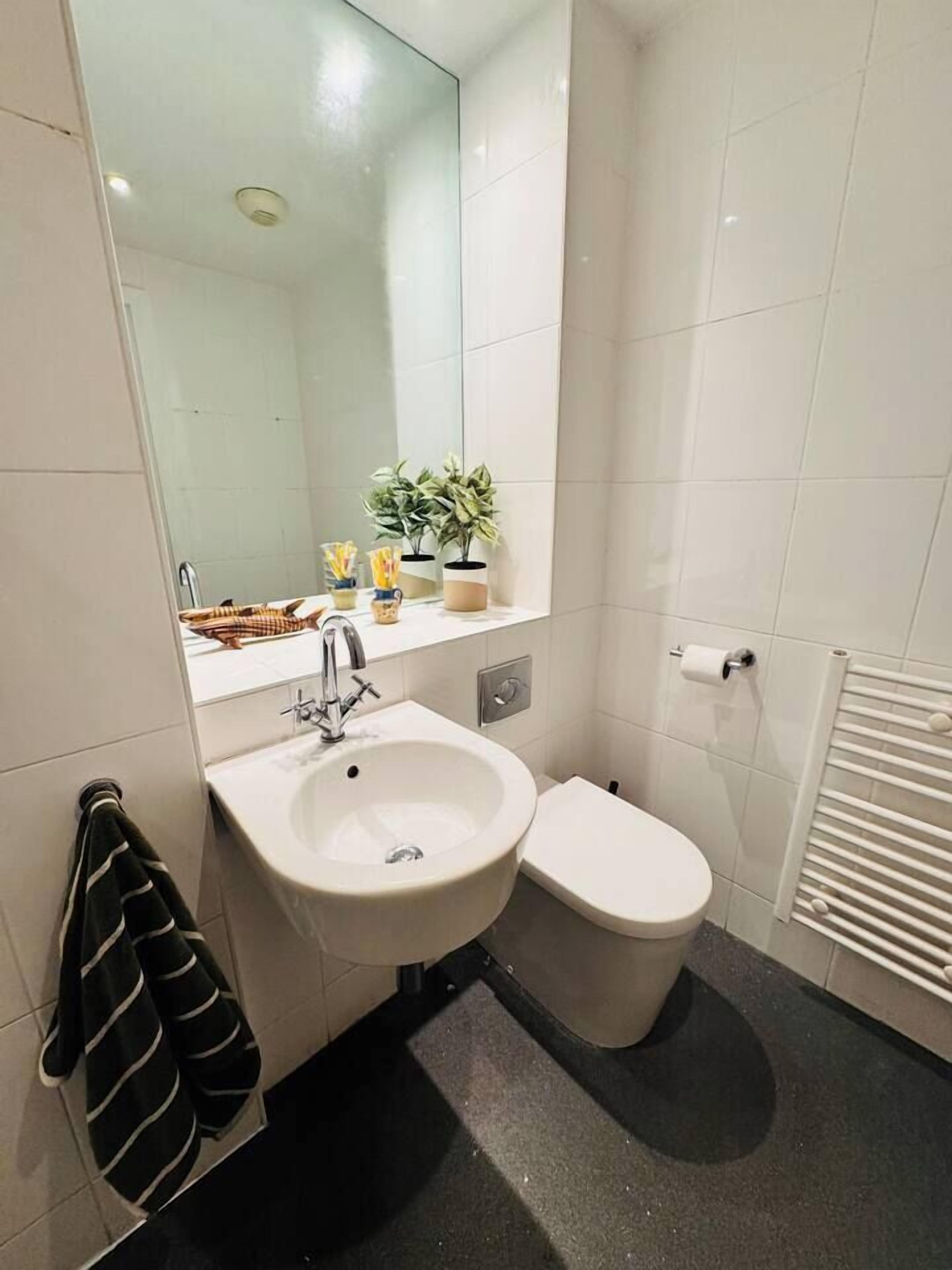 Baño con lavamanos blanco, inodoro y perchero para toallas.
