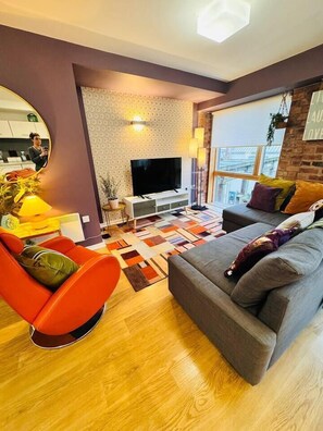 A modern living room with a sofa, a chair, a TV, and a patterned wall. - #12 CozyCanalsideLoft|near CoventryCathedral|for 6 (West Midlands)