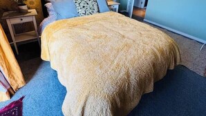 Ein Schlafzimmer mit einem Bett, einem Nachttisch, einer Lampe und einer Wand mit floralem Muster.