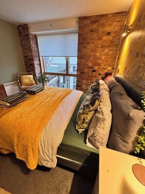A hotel room with a bed, a sofa, a window with a view, and a brick wall. - #12 CozyCanalsideLoft|near CoventryCathedral|for 6 (West Midlands)