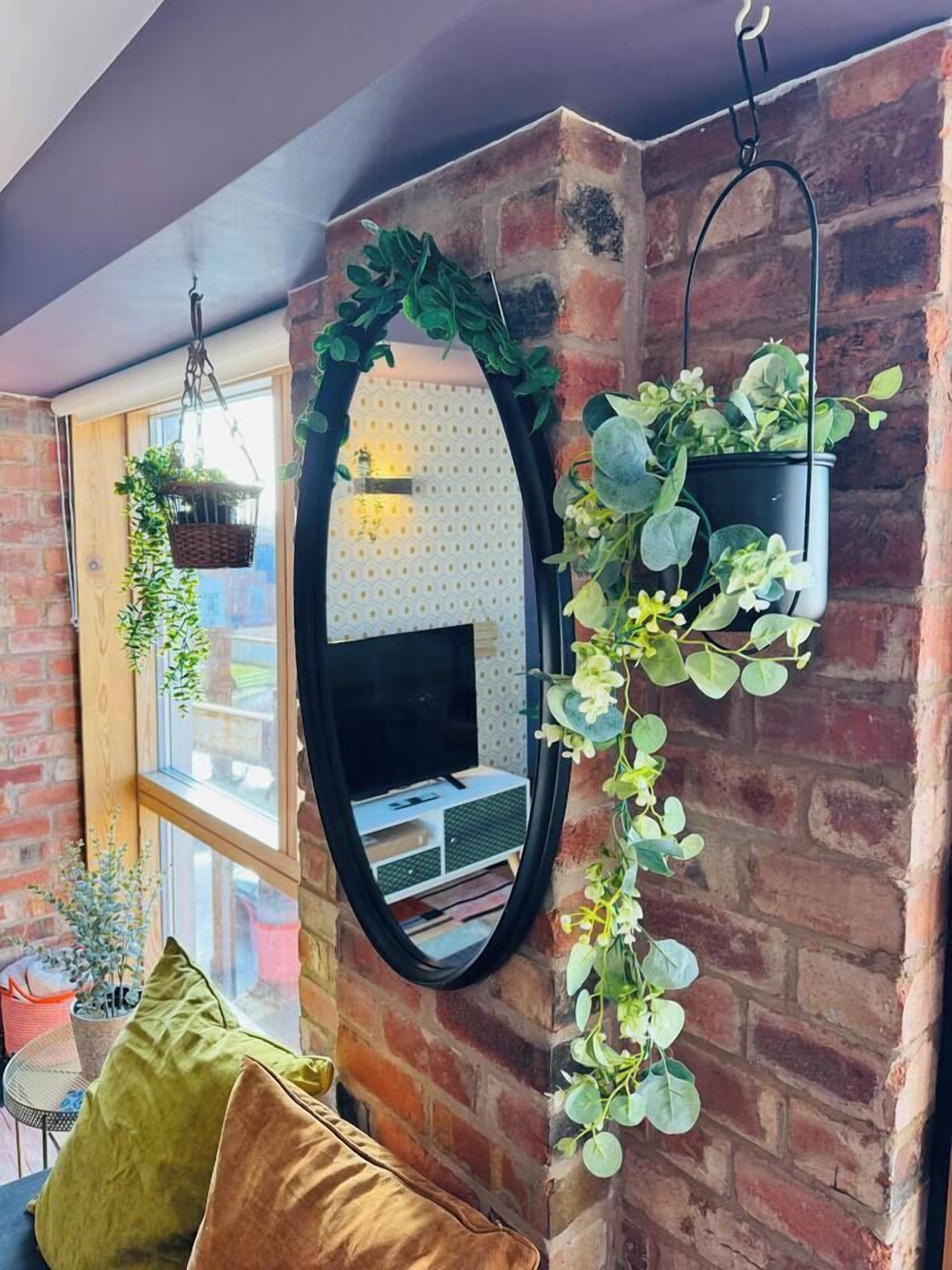 A room with a brick wall, a hanging plant, and a television.