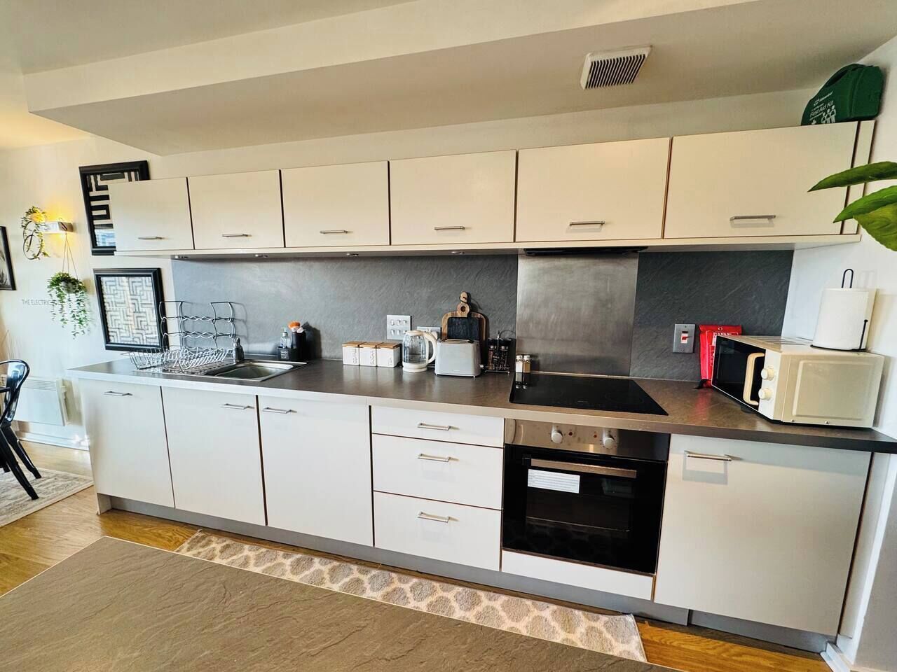 A modern kitchen with white cabinets, a stainless steel range, and a microwave.