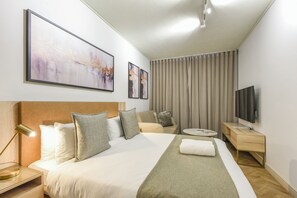 A hotel room with a large bed, a bedside table, a TV, and artwork on the wall. - One Rosebank: Elevated City Comfort (Johannesburg)