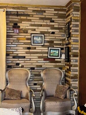 A room with a brick wall, two upholstered chairs, and framed pictures. - Welcoming 2-bedroom apartment with AC in vibrant Giza Governorate (Giza Governorate)