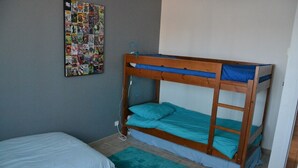 A bunk bed with a blue mattress, a single bed with a white mattress, and a wall-mounted comic book poster. - House Sleeps 14 + Pool + Air Conditioning + Outdoor Kitchen (Adissan)