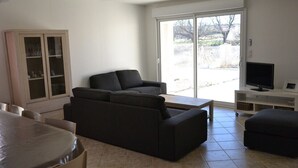 A living room with a sofa, a television, and a cabinet. - House Sleeps 14 + Pool + Air Conditioning + Outdoor Kitchen (Adissan)