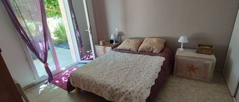 A bedroom with a bed, a nightstand, a lamp, and a window with curtains.