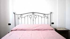 A single bed with a metal frame and a pink bedspread in a room with white walls and a small bedside table. - SNB002 - Pedaso, stunning portion of a villa with a swimming pool (Altidona)