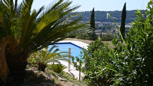 A swimming pool surrounded by lush greenery and a view of a distant town. - SNB002 - Pedaso, stunning portion of a villa with a swimming pool (Altidona)