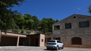 A building with a stone facade, a parked white vehicle, and a clear blue sky. - SNB002 - Pedaso, stunning portion of a villa with a swimming pool (Altidona)