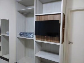 Ein Zimmer mit eingebauten Regalelementen, einem flachbildfernseher, der an einem der Regale befestigt ist, und einer Tür mit Griff.