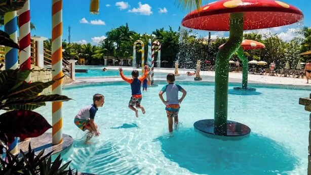 A water park with a pool, candy cane decorations, and umbrellas. - L'acqua di Roma III - 2 Premium Suites / Sleeps 4 (Caldas Novas)