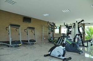 Een sportschool met loopbanden, elliptische trainers en een hometrainer.