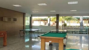 A billiards room with tables and a pool table, large windows, and a view of the outdoors. - L'acqua di Roma III - 2 Premium Suites / Sleeps 4 (Caldas Novas)