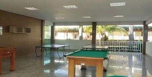 Ein Billardraum mit Tischen und einer Snookertisch, großen Fenstern und Blick ins Freie.