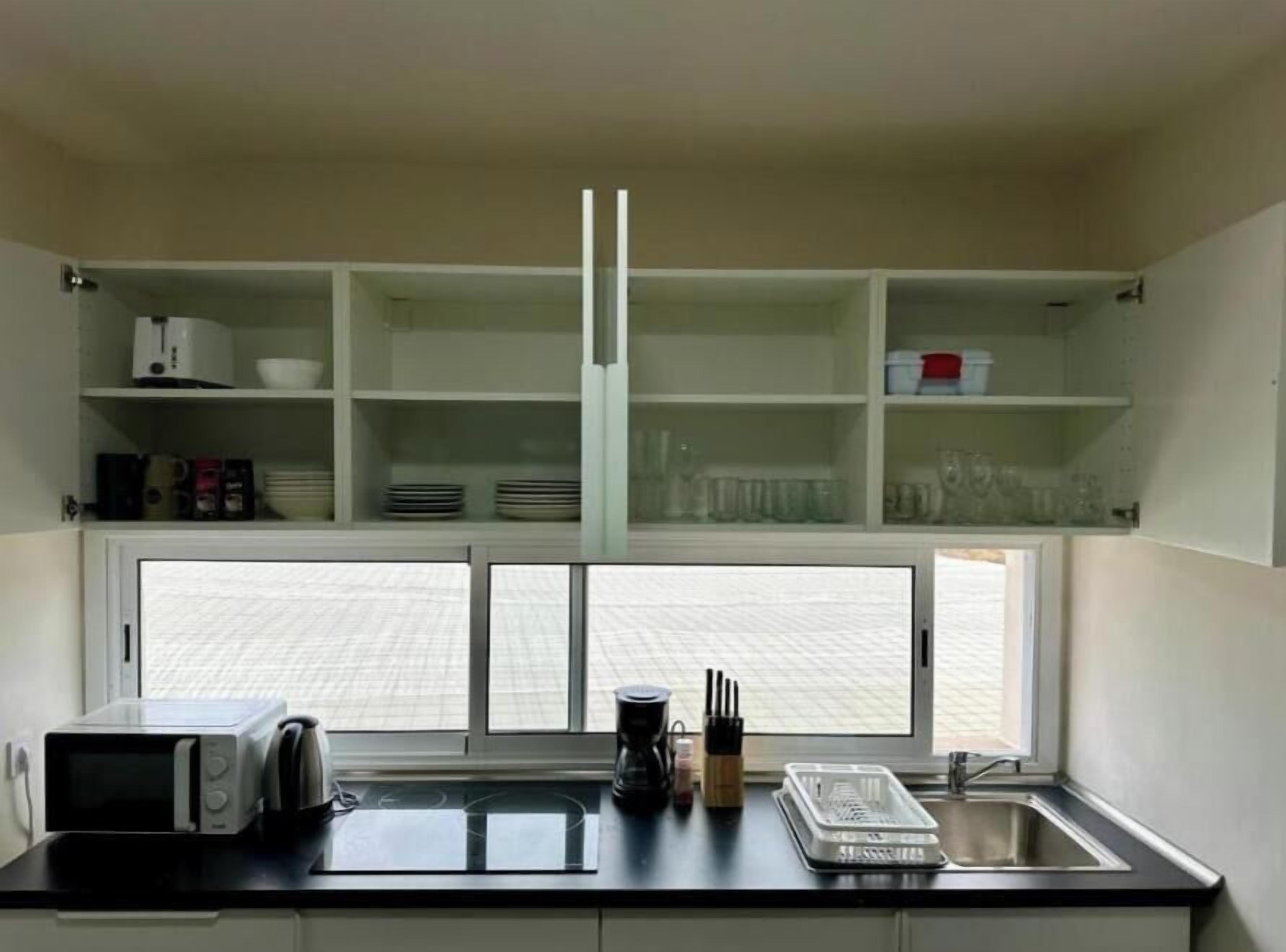 A kitchen with a microwave, toaster, sink, and cabinets.