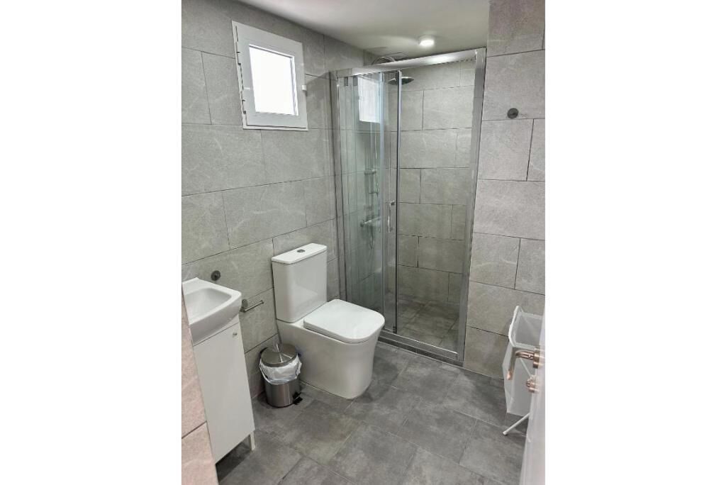 Een badkamer met een douchecabine van glas, een toilet en een wastafel.