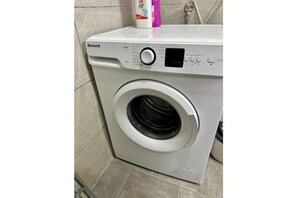 Eine Benavent Waschmaschine in einem Badezimmer mit gefliesten Wänden und Boden.