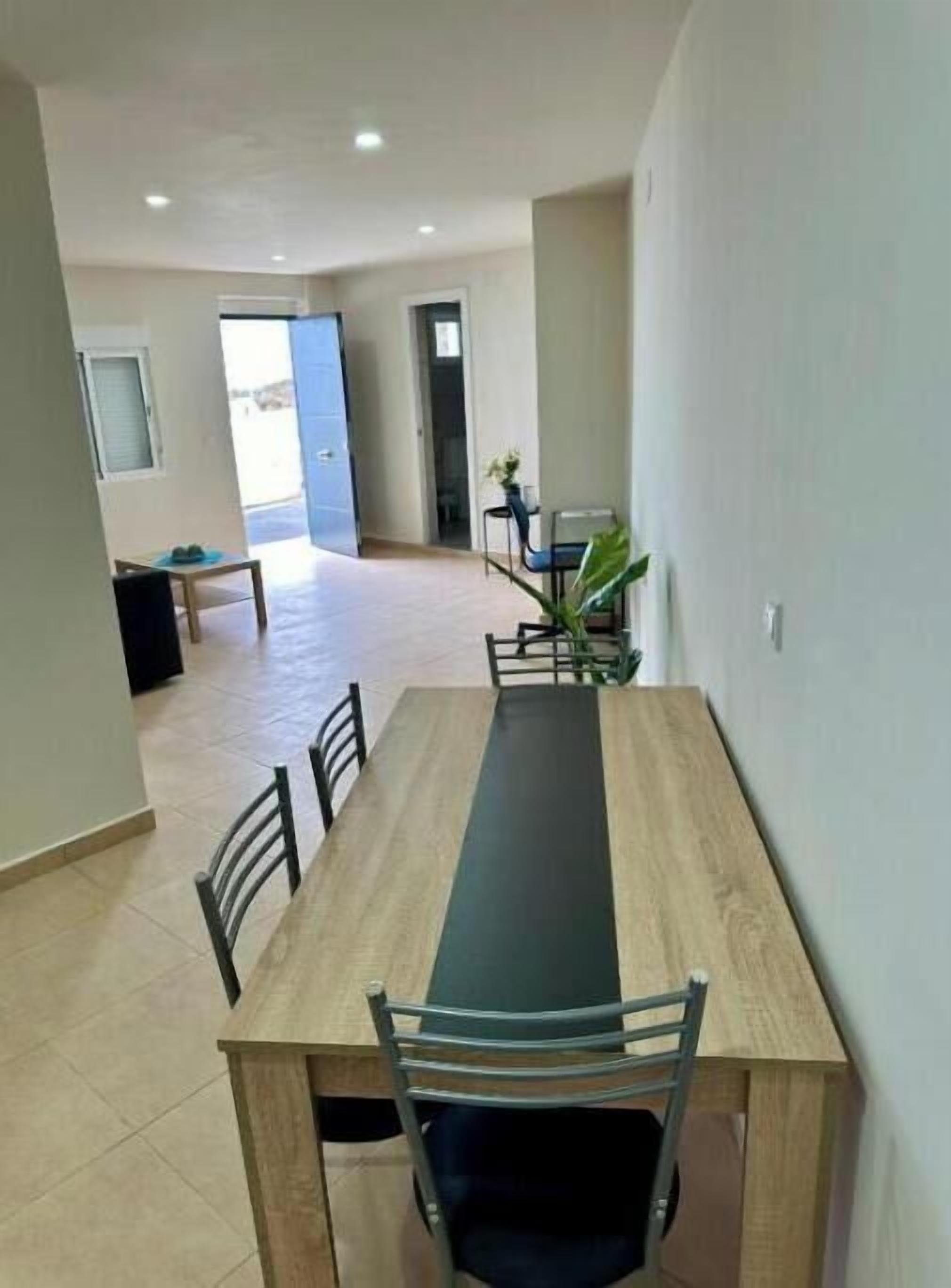 A dining area with a long table and chairs, a bench, and a potted plant.
