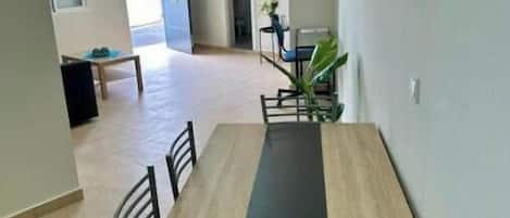 A dining area with a long table and chairs, a bench, and a potted plant.