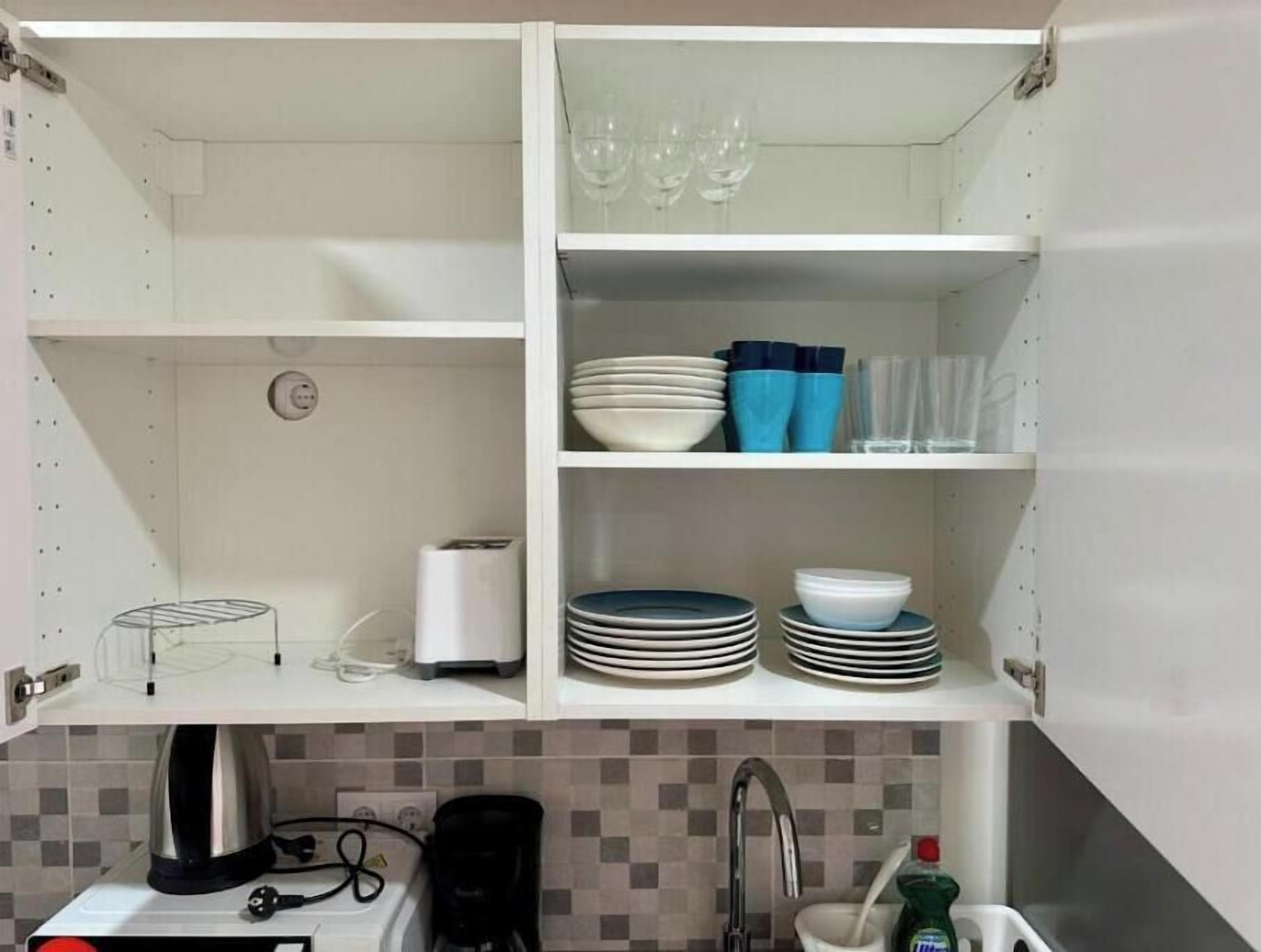 A kitchen with white cabinets, a coffee maker, and a sink.
