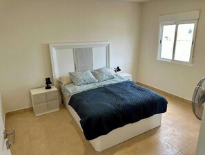 A bedroom with a bed, nightstands, a window, and a fan. - New modern apartment, Scandinavian style (Icod de los Vinos)