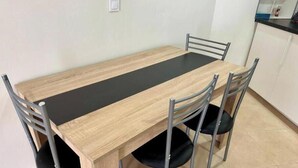 A dining table with four chairs, a black table runner, and a kitchen area in the background. - New modern apartment, Scandinavian style (Icod de los Vinos)