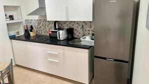 A kitchen with white cabinets, a stainless steel refrigerator, a black countertop, and a tiled backsplash. - New modern apartment, Scandinavian style (Icod de los Vinos)