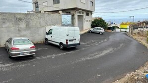 Un carrer amb una furgoneta blanca i un cotxe platejat aparcats al costat.