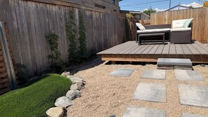 Eine Holzterrasse mit integriertem Sitzbereich und einem gepflasterten Weg.
