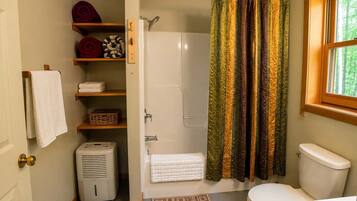 A bathroom with a shower, toilet, and a window.