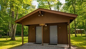 A wooden restroom with two doors, one labeled 'MEN' and the other 'WOMEN,' and a sign above stating 'LEAVE NO TRASH.' - River Cabin w/Kayaks, Fire Pit, WiFi & Game Room (Great Cacapon)