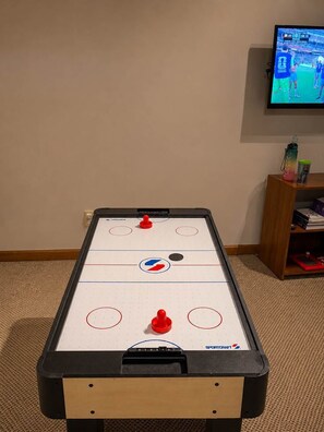 Een tafelhockey spel met een televisiescherm op de achtergrond.