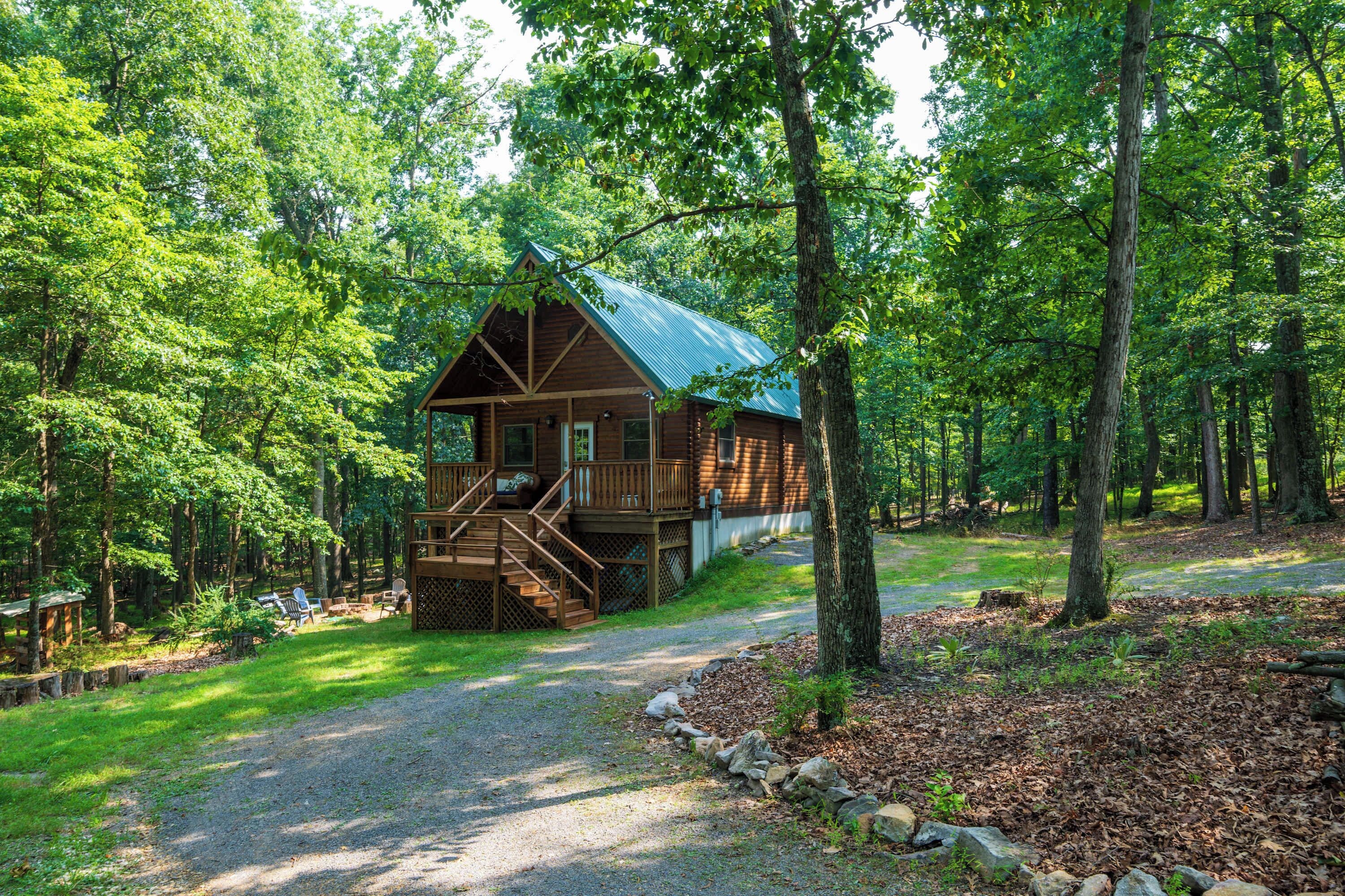 Een chalet met een veranda en een trap, omringd door een bos.