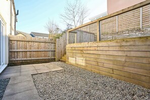 Ein Garten mit Holzzaun, Kiesfläche und Betonweg.