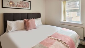 Een slaapkamer met een bed, een hoofdeinde, een raam en een inlijsting foto aan de muur.