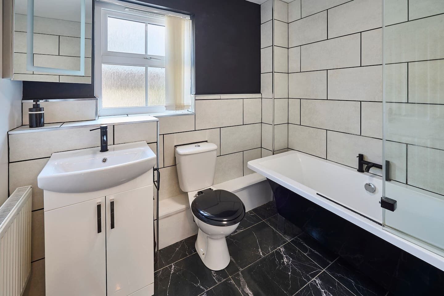Een badkamer met een witte wastafel, toilet en bad.
