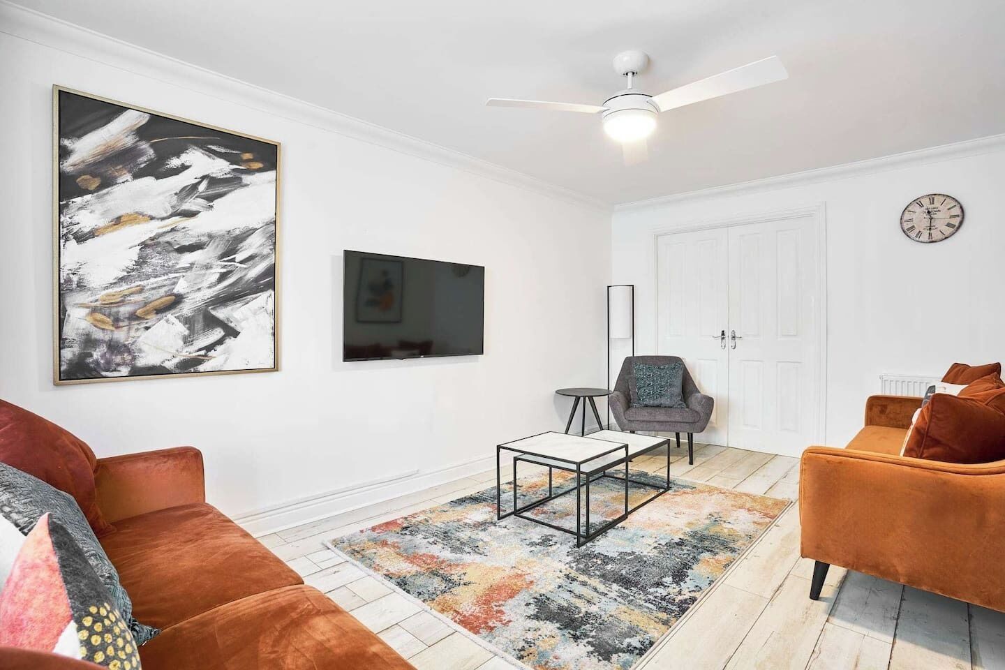 Una sala de estar con sofá, sillón, mesa de centro y una obra de arte en la pared.