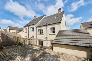 Un immeuble résidentiel doté d’un toit en pente, de nombreuses fenêtres et d’une terrasse en bois.