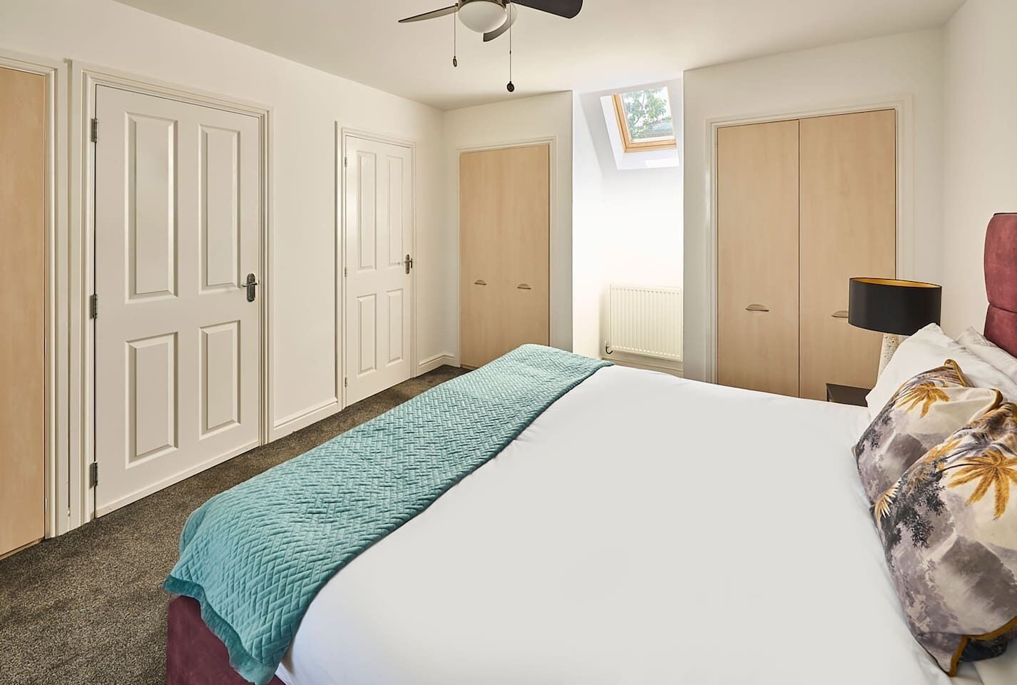 A bedroom with a bed, a ceiling fan, a window, and a radiator.