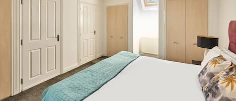 A bedroom with a bed, a ceiling fan, a window, and a radiator.