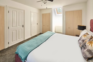 A bedroom with a bed, a ceiling fan, a window, and a radiator. - #112 Blueberry cottage Cornwall 4 bed 4 bathroom (Cornwall)